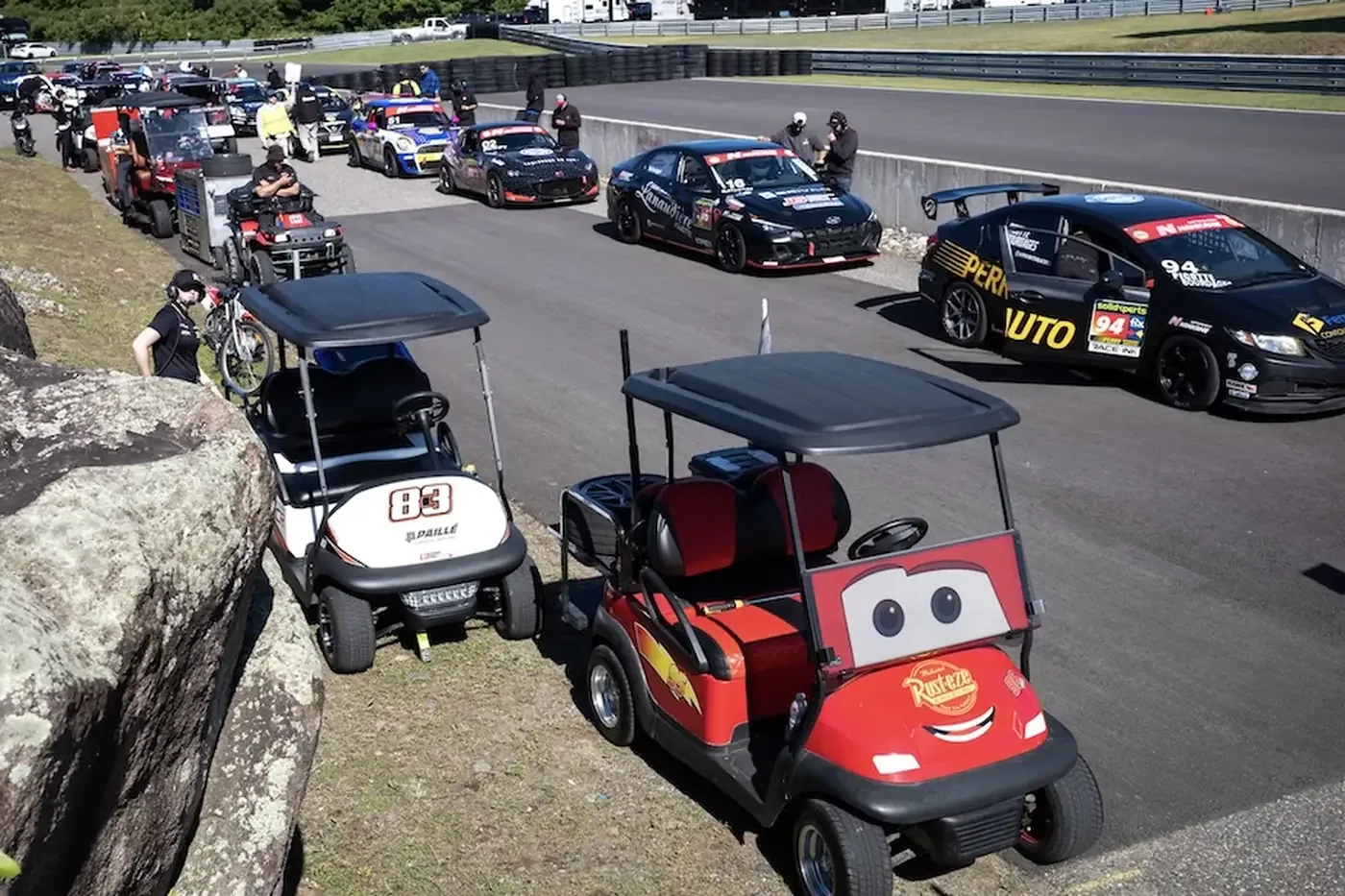 Touring cars and golf carts staging in the paddock at Calabogie