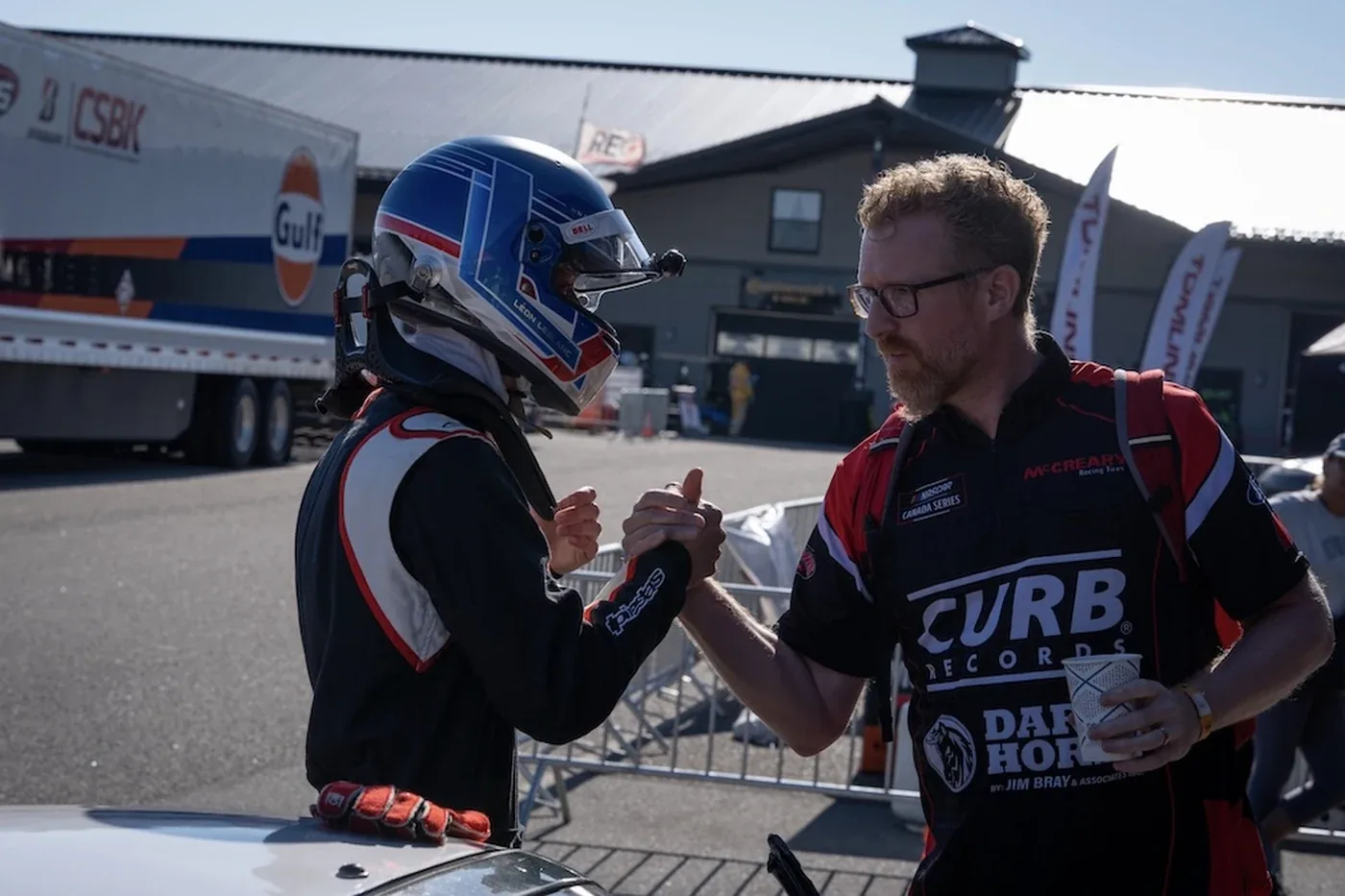 Two people shaking hands in the NASCAR Canada paddock at Calabogie