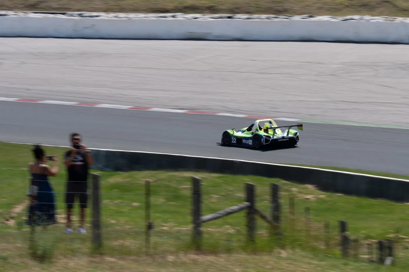 Spectators photographing the number 22 Radical from the fence at the track