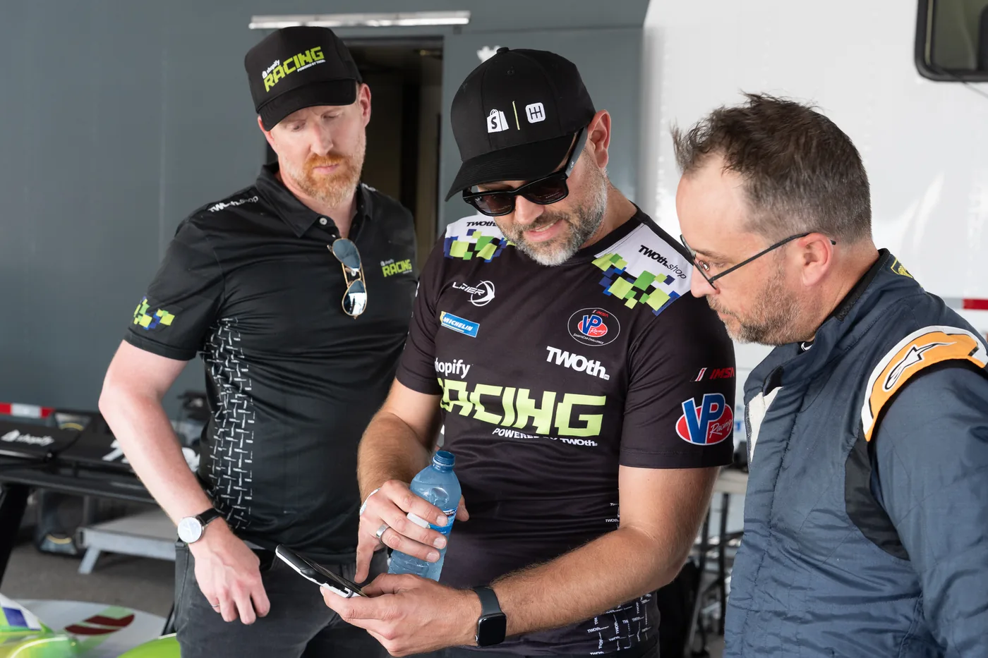 Francois Cote and coach Malcolm reviewing a phone with a TWOth team member in the paddock